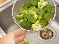 Broccoli bliver skyllet i en si