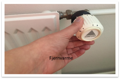 billedet viser en hånd der drejer på regulatoren på en radiator